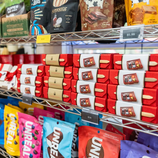 Shelves at Newbury Deli filled with packaged snacks, chocolates, and candy.