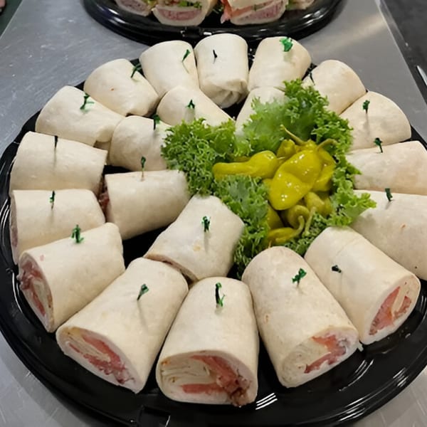 Newbury Deli catering tray with many deli wraps, garnished with lettuce and yellow peppers.